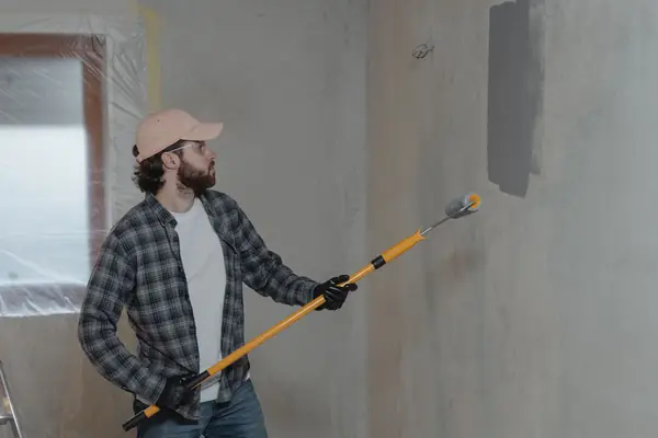 Painter rolling grey paint onto an interior wall in Provo